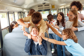 Classmates going to school by bus boy strangling kid angry while others trying to stop him