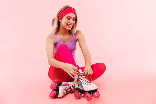 Image of smiling woman tying shoelace while sitting on floor