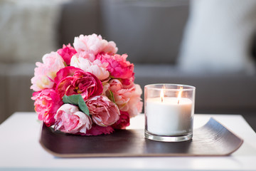 decoration, hygge and cosiness concept - burning fragrance candle and flower bunch at cozy home