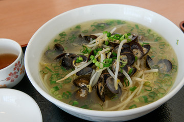 Top view of a bowl tasty Shijimi Clam and a glass of tea in Japanese restaurant