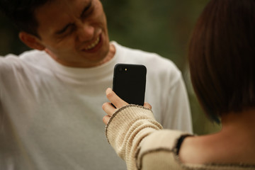 男性にスマートフォンの画面を見せる女性