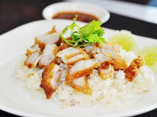 Fried pork on rice with coriander on the plate, eaten with spicy sauce, very tasty