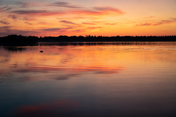 Fototapeta na wymiar Very romantic, full of orange and beautiful sunset on the lake, before forrest, Finland