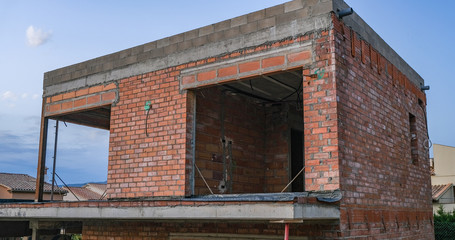 View of the building under construction against the backdrop of mountains and blue sky. Construction of a residential building in Europe. European building technology.