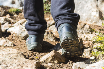 Person walking in the countryside with hiking boots between stones and plants