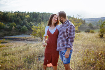 Beautiful couple are happy on a field at sunset.