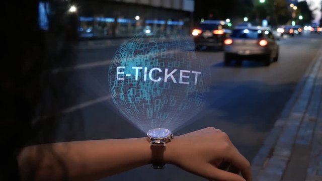 Unrecognizable curly woman with a hologram on smart watch with text E-ticket. Female hands with future holographic technology on the background of the night road