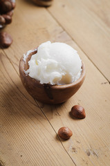 Shea butter in wooden bowl with nuts on old rustic table. Free text space.