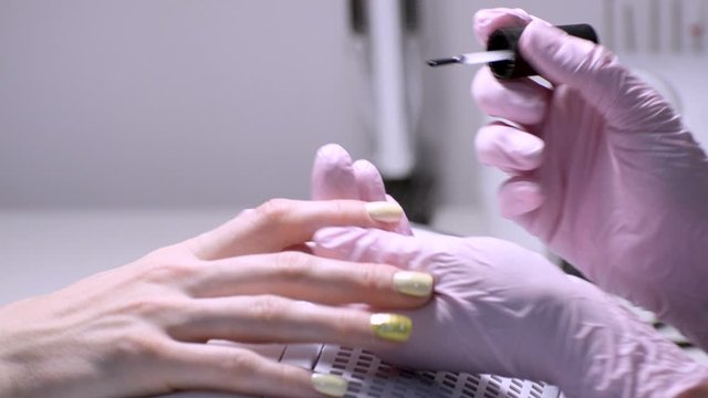 Master applies the topcoat on the nails. Close-up. Professional manicure. Beauty saloon.