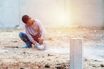 Selective focus on reinforced steel concrete pole with blurred worker cutting in background