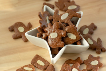Brown moravian dark gingerbreads with sliced almonds, christmas cookies in white star shapped bowl