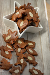 Brown moravian dark gingerbreads with sliced almonds, christmas cookies in white star shapped bowl