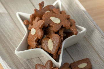 Brown moravian dark gingerbreads with sliced almonds, christmas cookies in white star shapped bowl