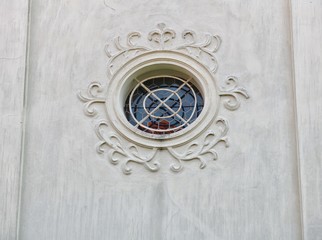 Round window with grille and reliefs on church in Tabor in south Bohemia.