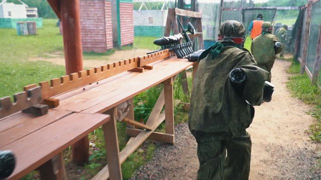 paintball players in camouflage uniforms take guns and run