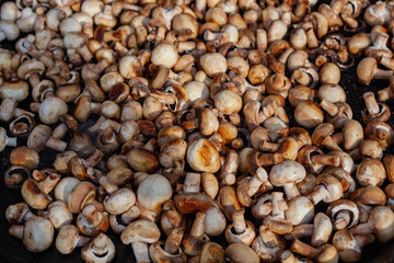 Lots of fried champignons in a large cast-iron skillet in the open air