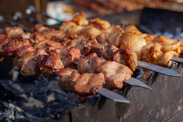 Meat on a skewer is fried on hot charcoal on an iron barbecue.