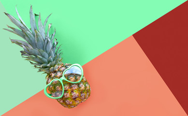 Funny pineapple in heart-shaped glasses on geometric diagonal background