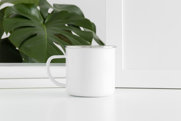 Enamel mug mockup with workspace accessories and a monstera plant.