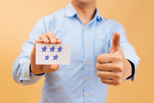 Businessman showing five stars card and thumbs up in bright yellow color background. Review, rating, ranking and evaluation concept