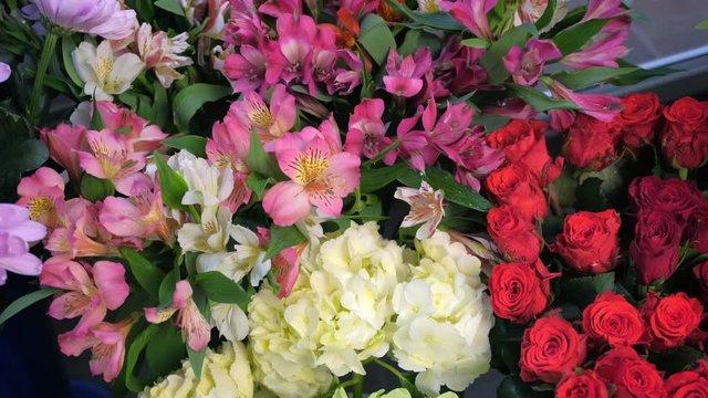 Beautiful different sorts of flowers roses, astra, azalea, alstroemeria, hydrangea, peonies, eucalyptus with water drops in vases in flower shop for sale, closeup view. Floral business concept.