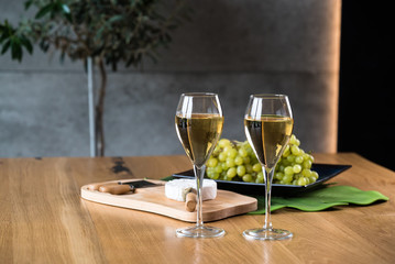 Pouring white wine into the glass above the table set with grape cheese appetizers