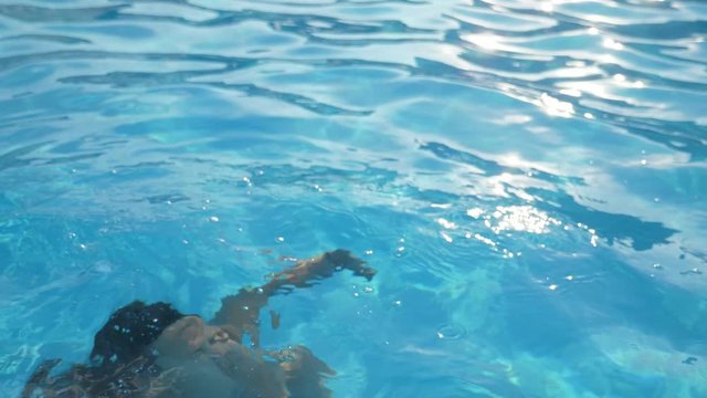 Happy woman emerging from water keeping her nose in swimming pool in slo-mo 