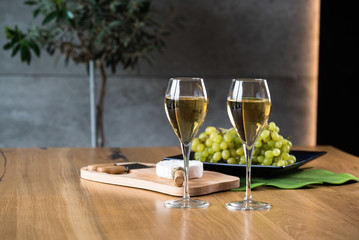 Pouring white wine into the glass above the table set with grape cheese appetizers