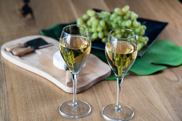 Pouring white wine into the glass above the table set with grape cheese appetizers
