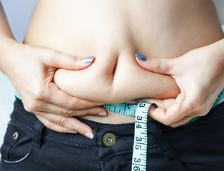 Close up of woman Hands Measuring Fat Belly which she feeling  gain weight.,sport, fitness and diet concept
