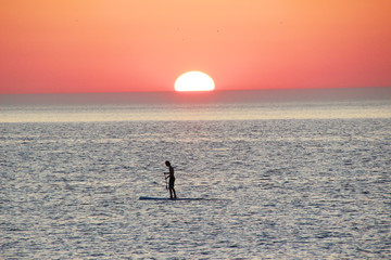 Paddle boarding, stand up paddling im Sonnenuntergang
