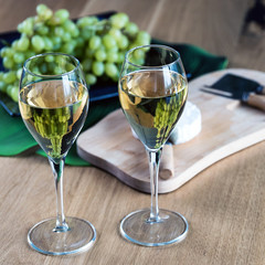 Pouring white wine into the glass above the table set with grape cheese appetizers