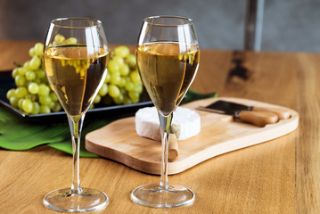 Pouring white wine into the glass above the table set with grape cheese appetizers