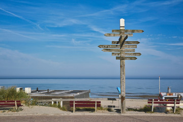  August 2019: Wooden signpost showing in multiple different directions at beach on island Texel - obrazy, fototapety, plakaty