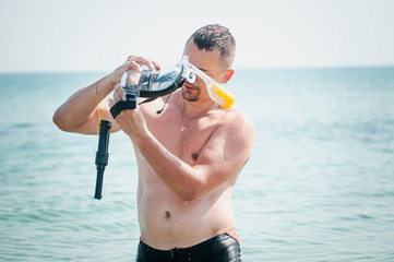 Man with swiming mask in the hand is going goes on water