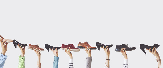 Hands holding different shoes on isolated background