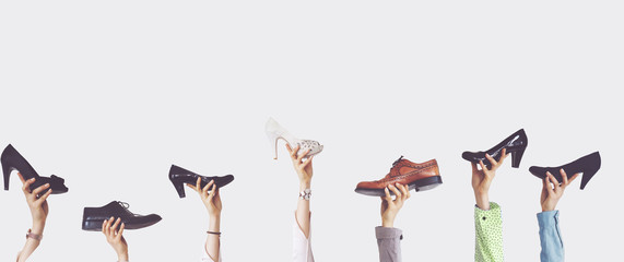 Hands holding different shoes on isolated background