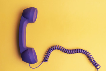 purple telephone receiver on yellow background - obrazy, fototapety, plakaty