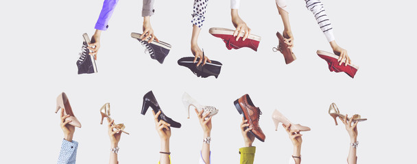 Hands holding different shoes on isolated background