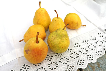 Yellow pears in the garden on a white tablecloth, carelessly scattered .The concept of the garden...