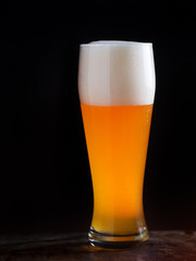 A glass of light beer on a dark background closeup