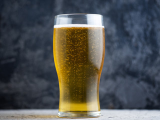 A glass of light beer on a dark background