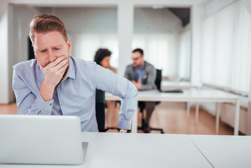 Troubled redhead businessman looking at laptop in the office, front view.