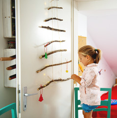 Little girl decorating Christmas tree with home made ornaments