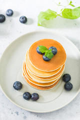 Sweet pancakes with honey and blueberries on the bright kitchen table
