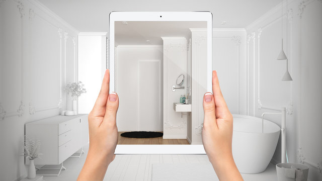 Hands holding tablet showing bathroom, notebook with blueprint sketch in the background, augmented reality concept, application to simulate furniture and interior design products