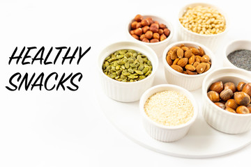 Top View of Variety of Nuts and Seeds on the White Background with Healthy Snacks Text Copy