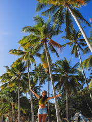 woman streching with palm trees on white sand beach at Paliton Beach in Siquijor Island, Philippines.  Tropical  summer vacation concept