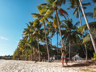 woman streching with palm trees on white sand beach at Paliton Beach in Siquijor Island, Philippines.  Tropical  summer vacation concept