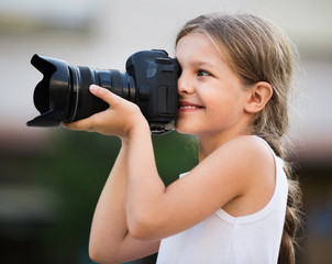 Girl taking pictures with professional camera outdoors